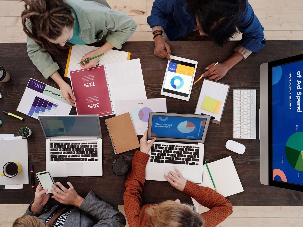 Marketing team planning a content calendar around a table of laptops and charts